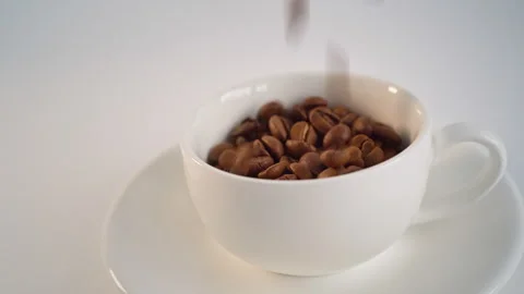 Coffee beans are poured into a white cup. Video stock 242773445