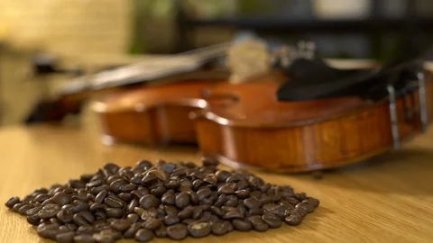 Coffee beans are pured on the table next to the violin. 4K Stock Footage 102548837