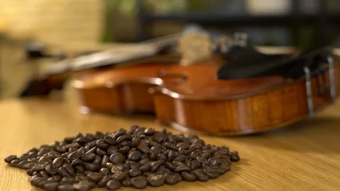 Coffee beans are pured on the table next to the violin. 4K Video stock 102548868