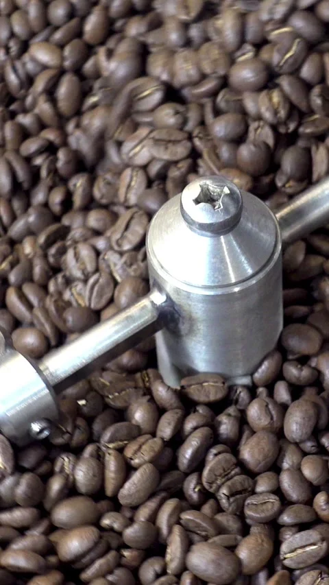 The coffee beans are stirred by a rotating metal stirrer. Stock Footage 339233213
