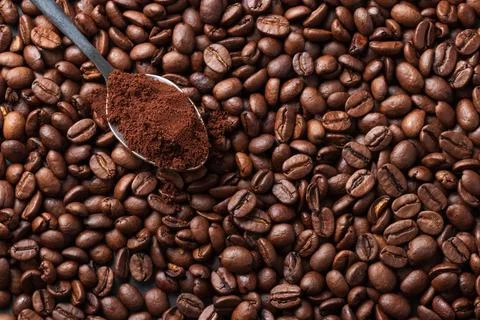 Coffee beans background with coffee beans and a teaspoon of ground coffee Stockfoto's