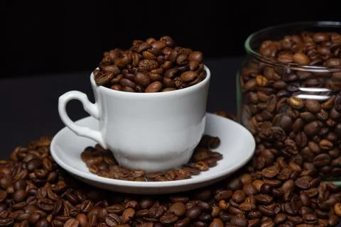 Coffee beans on a black background. A coffee cup full of coffee beans Stock Photos