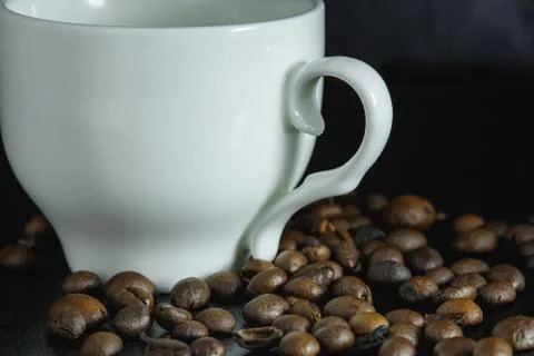 Coffee beans on a black surface, a large number, scattered, close-up, next is Stock Photos