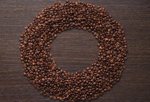 Coffee beans in bulk in the form of rings on the background of dark wood Stock Photos