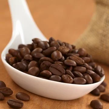 Coffee beans on ceramic spoon Stock Photos
