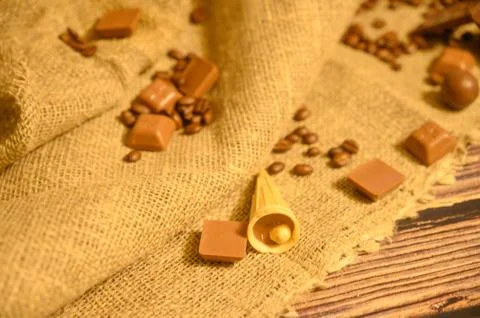 Coffee beans, chocolate, cake in a waffle cone on a background of rough homes Stock Photos