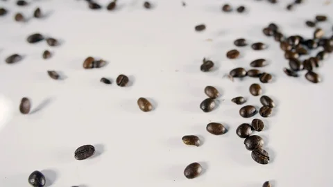 Coffee beans close up sprinkled onto a white background, with a macro dolly shot Stock Footage 88513724