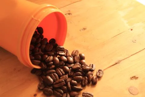 Coffee beans in coffee container isolated on wooden Foto stock