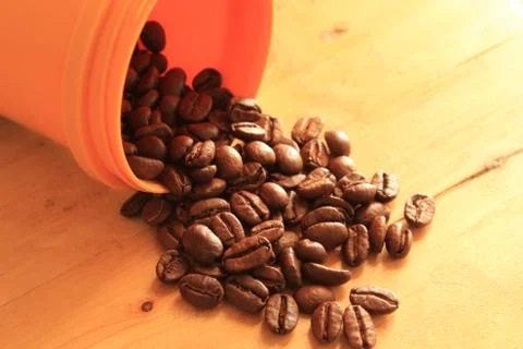 Coffee beans in coffee container isolated on wooden Foto stock