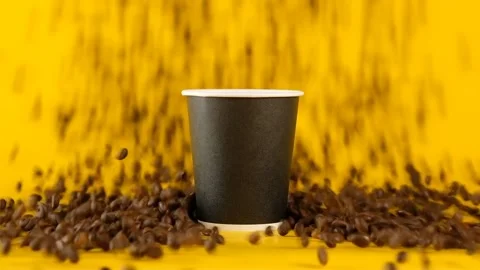 Coffee beans fall next to paper coffee cup isolated on yellow background. Stock Footage 237218151