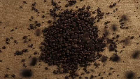 Coffee beans fall into a pile on a burlap bag Stock Footage 202149276