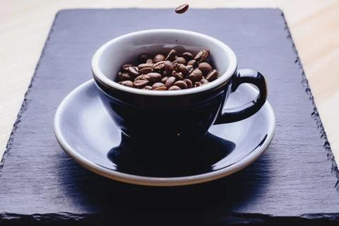 Coffee beans falling to cup Stock Photos