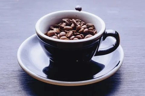 Coffee beans falling to cup Stock Photos