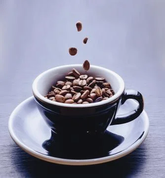 Coffee beans falling to cup Stock Photos