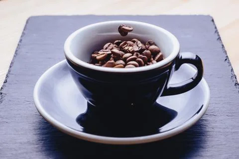 Coffee beans falling to cup Stock Photos