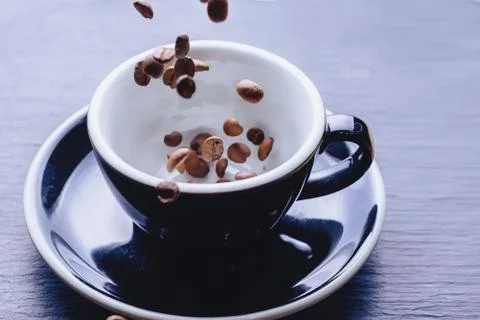 Coffee beans falling to cup Stock Photos