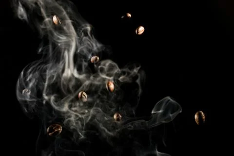 Coffee beans falling down trough smoke over black background - isolated Stock Photos