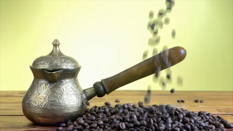 Coffee beans falling down on wooden table near vintage turkish coffee pot Stock Footage 148095293