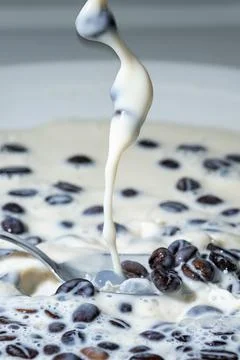 Coffee beans falling on the milk splash. Stock Photos