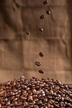 Coffee beans falling on a mountain of roasted coffee beans, close-up. Foto stock