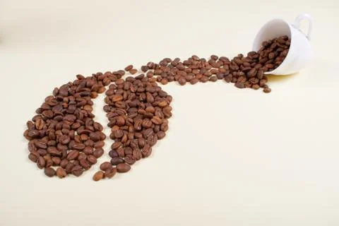 Coffee beans falling out of white cup. Stock Photos