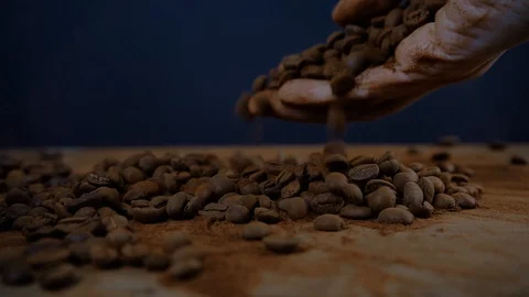 Coffee beans falling on a table on dark background, coffee in a hand slow motion Video stock 125401851