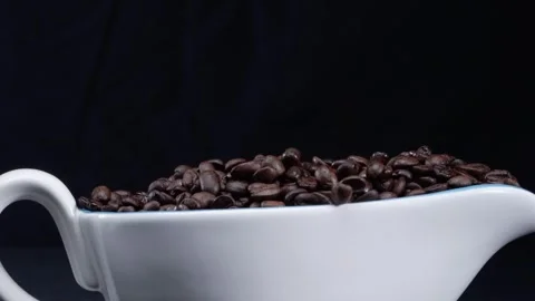 Coffee beans falling into white cup with separated black background. Pabulum. Video stock 283502202
