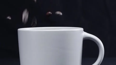 Coffee beans falling into white cup with separated black background. Pabulum. Video stock 293222346