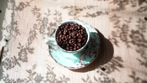 Coffee beans falls out the beautiful cup.There is a beautiful shadow on the Stock Footage 133821965
