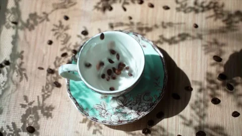 Coffee beans falls on a table in the beautiful cup. There is a beautiful shadow Stock Footage 133817332