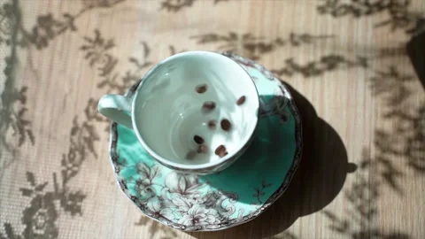 Coffee beans falls on a table in beautiful cup. There is a beautiful shadow in Stock-Footage 133817766