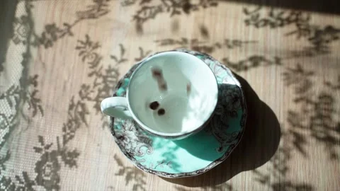 Coffee beans falls on a table in cup. Hand puts a spoon into the cup. There is a Stock-Footage 133820815