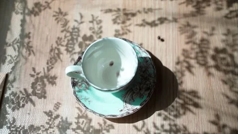 Coffee beans falls on a table in cup. Hand puts a spoon into the cup. There is a Stock-Footage 133821220