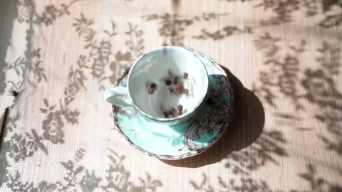 Coffee beans falls on a table in cup. Hand puts a spoon into the cup. There is a Stock Footage 133822177