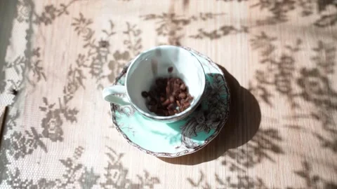 Coffee beans falls on a table in cup. Hand puts a spoon into the cup. There is a Stock Footage 133822391