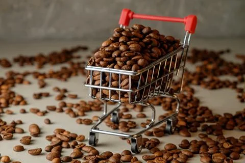 Coffee beans fill a tiny shopping cart on an artistic background Stock Photos
