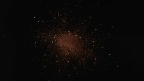 Coffee beans fly after being exploded against black background. Slow Motion. Stock Footage 79731976