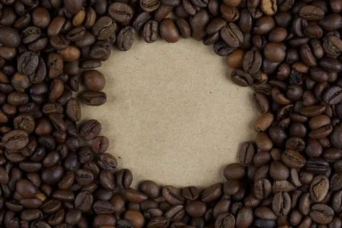Coffee beans forming a circular frame on kraft paper Stock Photos