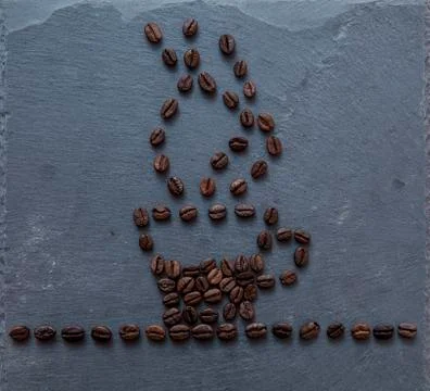 Coffee beans on gray stone shaped as coffee cup filled with coffee smoking Stock Photos