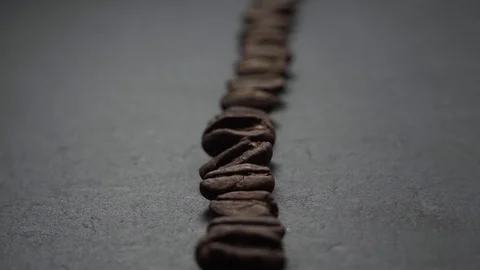 Coffee beans lie in row on stone. The camera slowly fly forward over coffee. Stock Footage 127460003