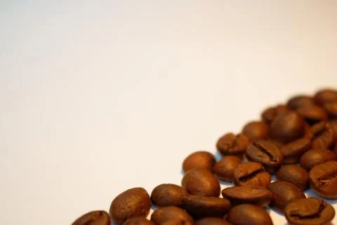Coffee beans on light beige background. Stock Photos