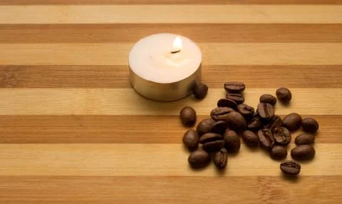 Coffee beans, a lighted candle Stock Photos