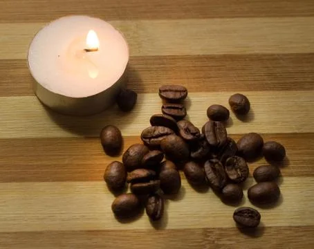 Coffee beans, a lighted candle Stock Photos