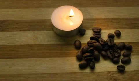 Coffee beans, a lighted candle Stock Photos
