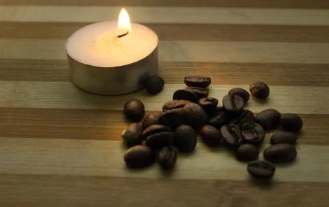 Coffee beans, a lighted candle Stock Photos
