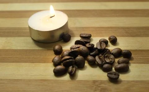 Coffee beans, a lighted candle Stock Photos