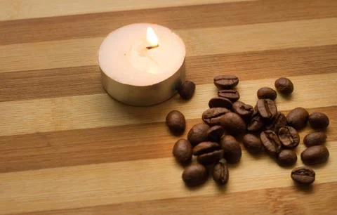 Coffee beans, a lighted candle Stock Photos