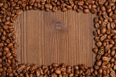 Coffee beans make a frame for a place with text on a wooden background. 스톡 사진