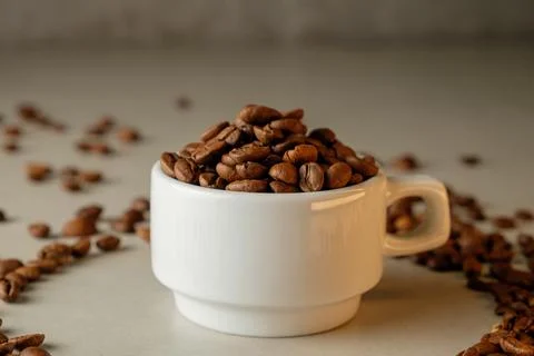 Coffee beans overflow from a white cup, creating a rustic coffee ambiance Stock Photos