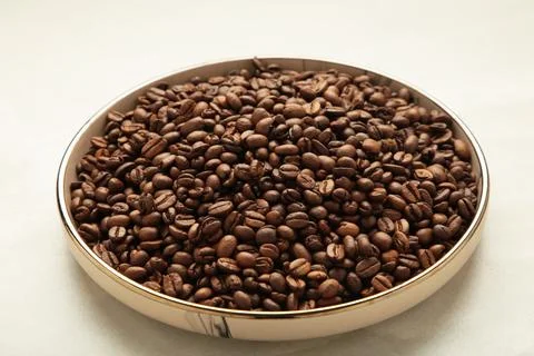 Coffee beans on plate on light background Stock Photos